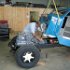 The transmission and engine are installed as an assembly. The cab not yet bolted to the frame, is tilted back to allow the shift lever to pass under the firewall. John is working on the clutch linkage.